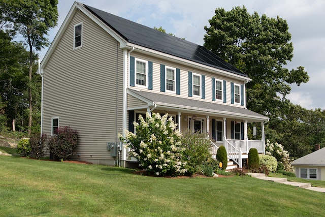 White two-story house with blue shutters and a large green lawn